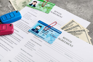 Rental agreements, driver licenses, money and car keys on grunge background, closeup