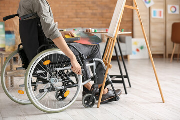 Young handicapped artist painting in workshop