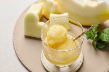 Bowl with delicious sorbet, melon pieces and mint on light background