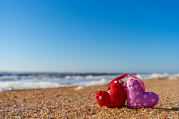 Image of a soft toy in the shape of a heart on the beach.