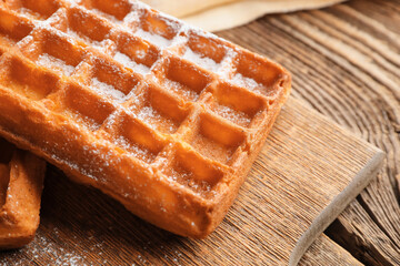 Board with delicious Belgian waffle on wooden background, closeup