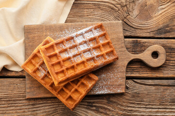 Board with delicious Belgian waffles on wooden background