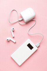 Obraz premium Modern power bank and case for earphones on pink background