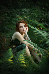 Romantic portrait of a woman in a fern in the forest. Art woman natural makeup resting in nature. Green fern thickets