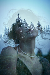 Portrait of a girl with double exposure against a tree crown. Delicate mysterious portrait of a woman with a blue sky in wood