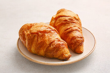 Plate with delicious croissants on white background