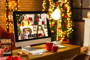 Computer on table in dark room. Celebrating Christmas online due to coronavirus epidemic