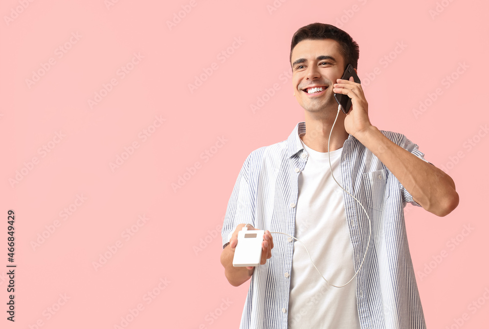 Poster young man with phone and power bank on color background