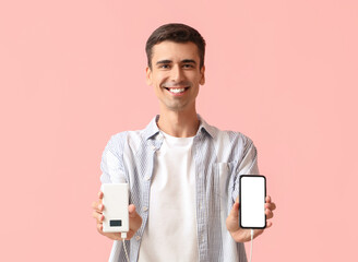 Young man with phone and power bank on color background