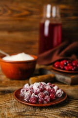 Plate with delicious sugared cranberry on wooden background