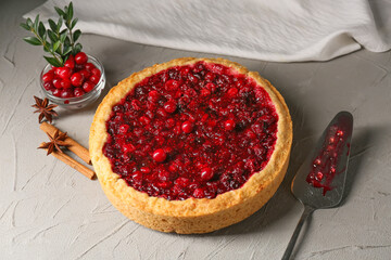 Tasty lingonberry pie and spices on light background