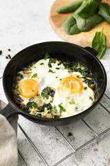 Frying pan with tasty Shakshouka and ingredients on light background