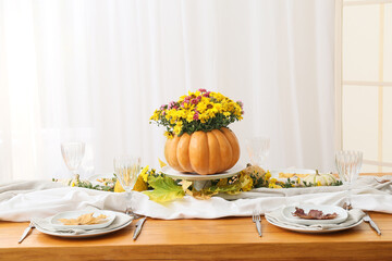 Beautiful bouquet of autumn flowers in pumpkin on served table