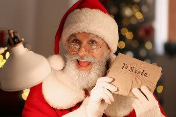 Happy Santa Claus with letters at home on Christmas eve