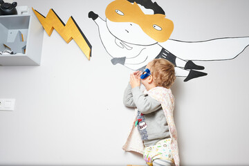 Little superhero admiring wall decoration