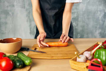 Cook woman on the kitchen cutting vegetables cutting board