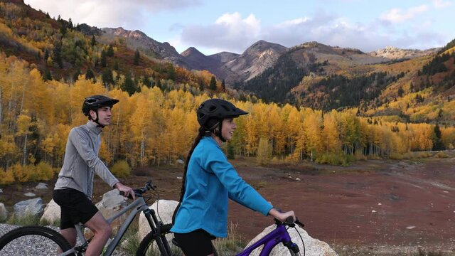 Couple on mountain bikes stop to look at the beautiful Autumn view in the Utah mountains.