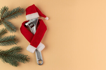 Adjustable spanner in Santa Claus hat on beige background.