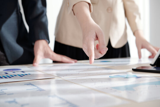 Close-up image of female entrepreneur pointing at line chart in report, selective focus