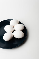 chicken eggs in a bowl and on a plate on a white background