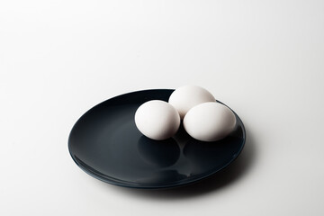 chicken eggs in a bowl and on a plate on a white background