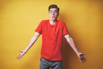Don't know! Confused young man against yellow background.