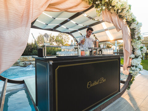 Bartender Mixing Cocktails And Drinks Outdoor At Sunset Near A Pool In A Venue Location