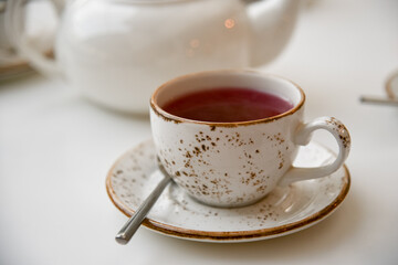 A white cup of tea and a kettle. Morning. Breakfast.