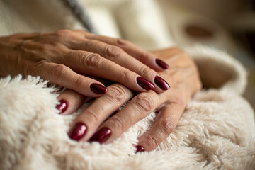 Elegant female manicure and royal colored nails. Lady beauty treatment in salon and spa. Dark red hybrid polish. Selective focus on the details, blurred background. - obrazy, fototapety, plakaty