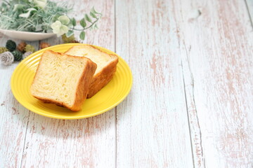 黄色のお皿に乗せたデニッシュと観葉植物｜右スペース