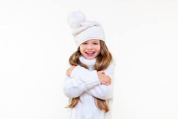 a beautiful little girl in a warm sweater and a winter hat is smiling. Warm children's clothing.