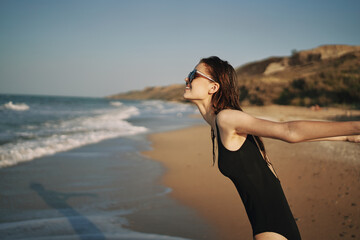 Fototapeta na wymiar woman walks along the sandy shore in a black swimsuit sun tropics