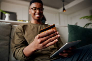 Young adult black male making online purchase on sofa relaxed and happy