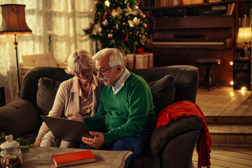 Obraz premium Couple sitting on sofa and using laptop
