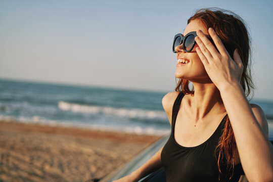 woman on the beach is with a car wearing sunglasses travel