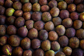 Lots of ripe figs in a box on the market. Top view. Delicious seasonal fruit. Close-up. Vitamins and health from nature.