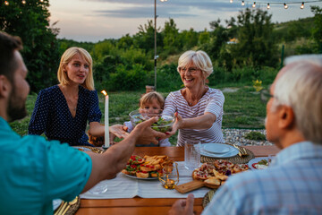 Cheerful family enjoying a family dinner outside at home during evening