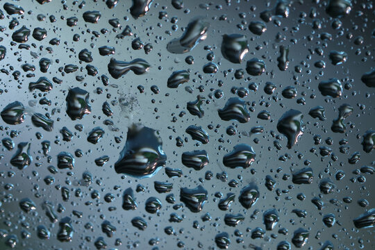Raindrops on a glass, macro, cold color, rainy gray day,