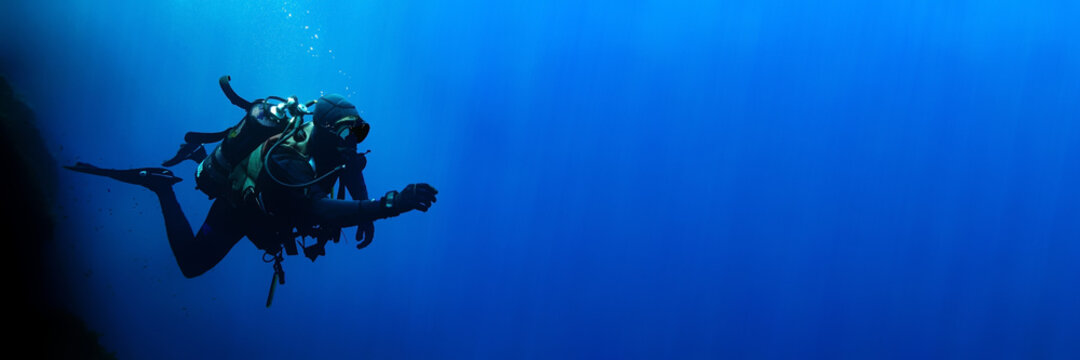 Technical scuba diver in a horizontal position with sun rays blue background