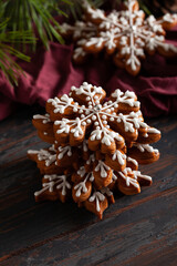 Christmas background with homemade snowflake shape gingerbread cookies on wooden background. New Year celebration traditions concept.