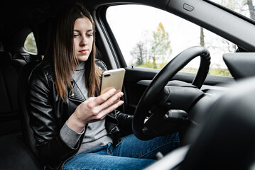 Young woman using mobile phone while driving car.
