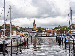 Fototapeta premium Sail boats in the port of Flensburg, St. Jorgen's Church in the background. Schleswig-Holstein in Germany