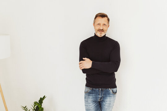 Attractive trendy middle-aged man standing with folded arms