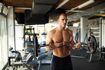 Fototapeta na wymiar Young fit man exercising in a gym to stay healthy. Sport people workout concept