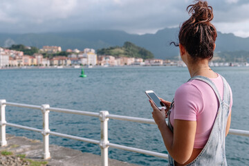 Fototapeta na wymiar Horizontal view of unrecognizable woman using technology. Caucasian woman with smartphone on holidays in Asturias. Travel destination and technology concept.