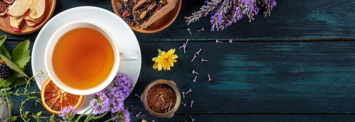 Organic tea panorama, shot from above with copy space. Herbs, flowers and fruit around a cup of tea...