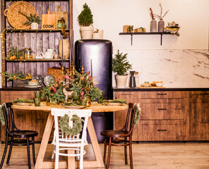 Festive kitchen in Christmas decorations. Candles, spruce branches, wooden stands, table laying