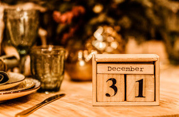 wooden calendar with date of 31 december stands on the table against the background of a festive...
