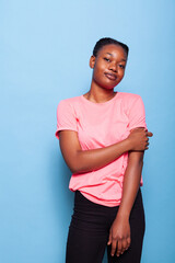 Portrait of african american young woman smiling at camera standing posing during photography session standing in studio. Friendly joyful teenager over blue background. Relaxation concept