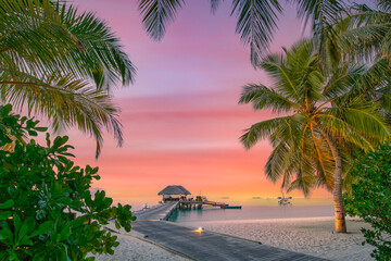 Sunset on Maldives island, luxury water villas resort and wooden pier. Beautiful sky and clouds and...